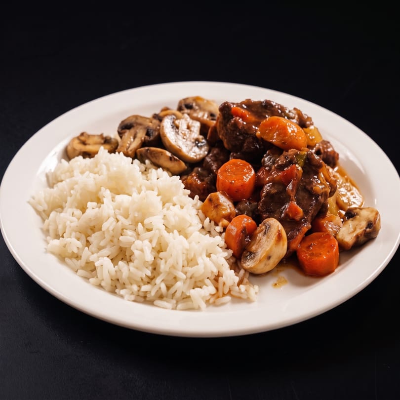 A white plate with a serving of white rice and beef stew with carrots and mushrooms.